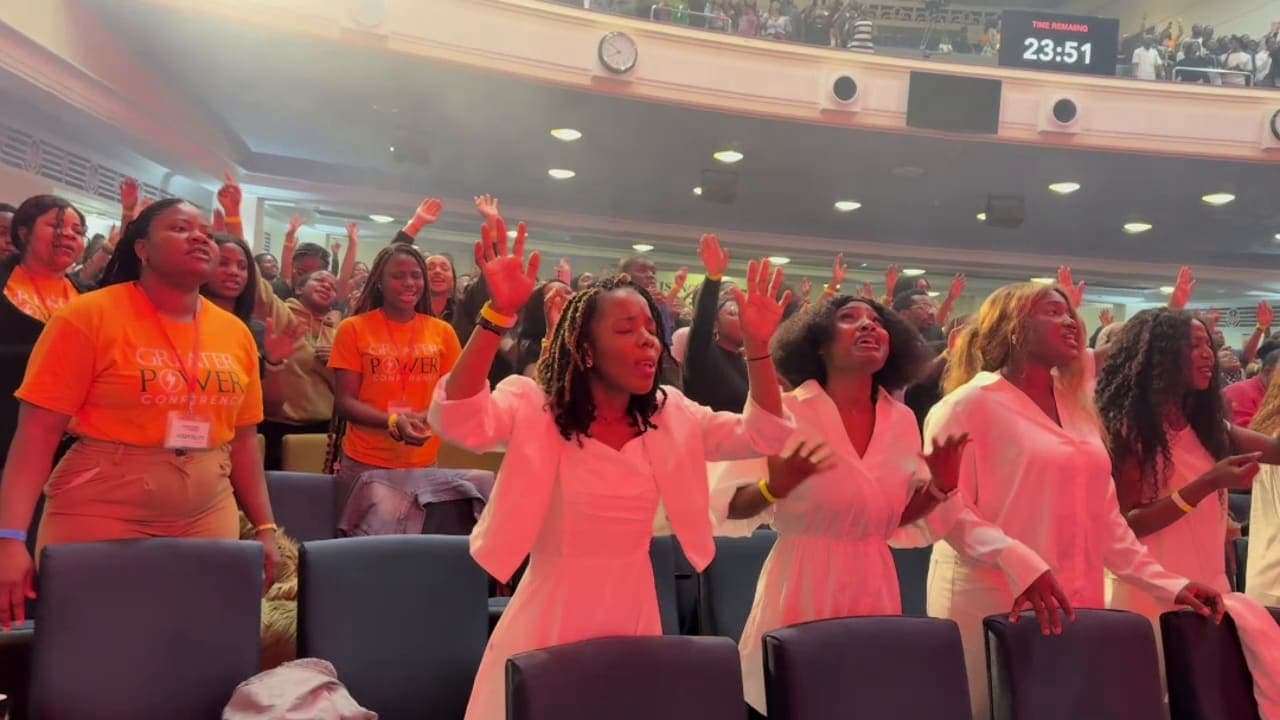 Women in white worshipping with raised hands at the Greater Power Conference